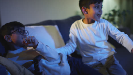 Dos-Niños-Pequeños-En-Casa-Divirtiéndose-Jugando-Con-La-Consola-De-Juegos-De-Computadora-En-La-Televisión-Peleando-Por-Los-Controladores-A-Altas-Horas-De-La-Noche-6